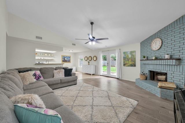 living room featuring visible vents, a brick fireplace, wood finished floors, ceiling fan, and vaulted ceiling
