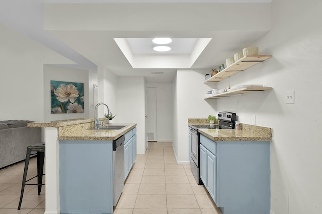 kitchen with a sink, a raised ceiling, appliances with stainless steel finishes, and blue cabinets