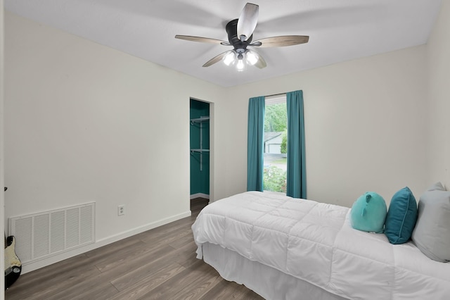 bedroom with a ceiling fan, visible vents, wood finished floors, baseboards, and a closet