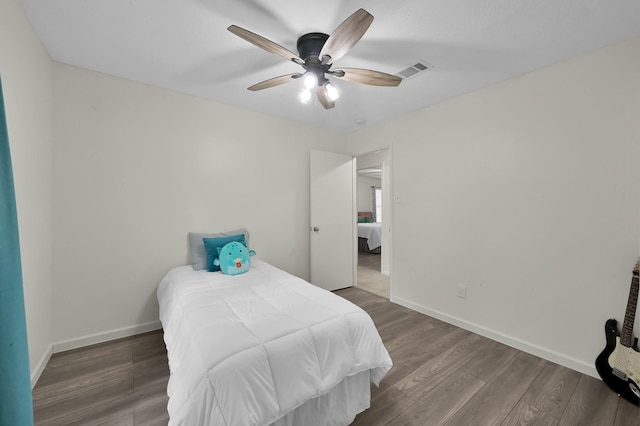 bedroom with baseboards, a ceiling fan, wood finished floors, and visible vents