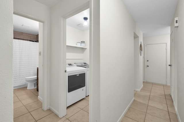 hall with separate washer and dryer, baseboards, and light tile patterned flooring