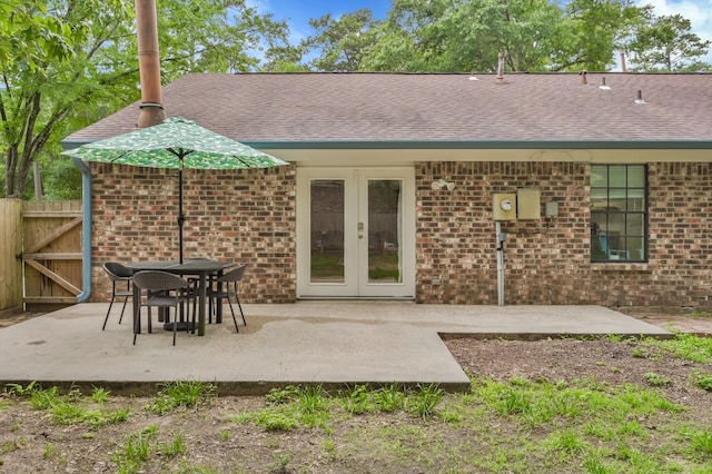 back of property with fence, a patio, french doors, brick siding, and a shingled roof