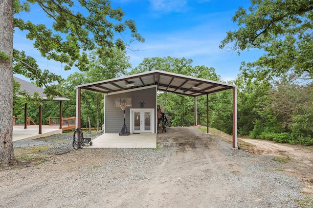 exterior space with french doors, a detached carport, and dirt driveway