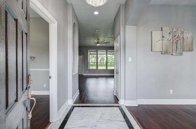 entrance foyer featuring arched walkways, baseboards, a ceiling fan, and wood finished floors