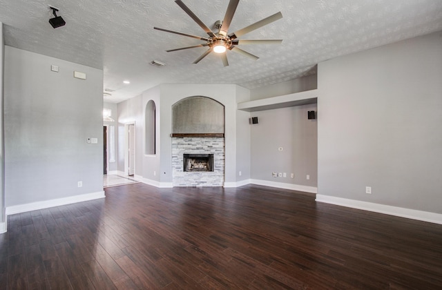 unfurnished living room featuring ceiling fan, a fireplace, a textured ceiling, wood finished floors, and visible vents