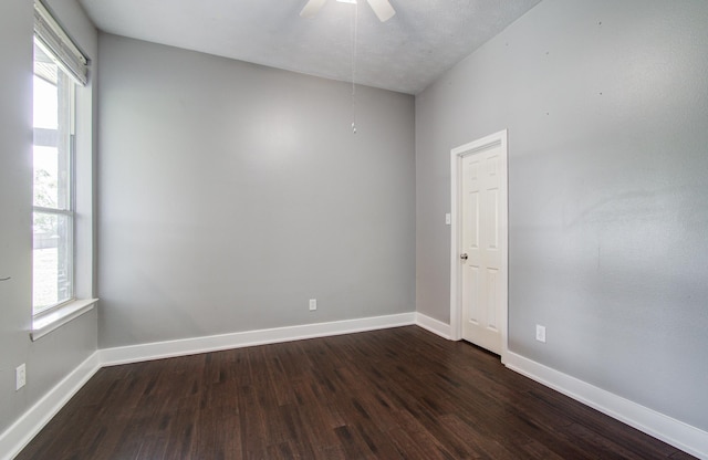 unfurnished room featuring baseboards, a ceiling fan, dark wood-style flooring, and a wealth of natural light