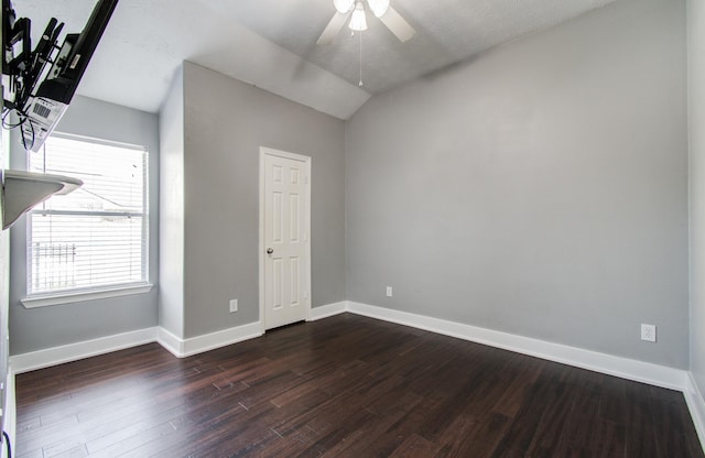spare room featuring baseboards, ceiling fan, vaulted ceiling, and dark wood-type flooring