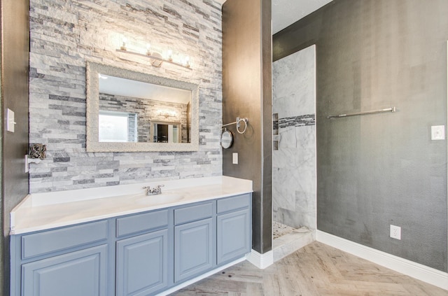 full bathroom with baseboards, tiled shower, and vanity