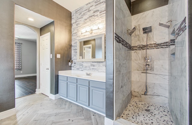 bathroom with baseboards, vanity, and tiled shower