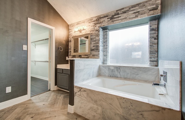 bathroom with vanity, baseboards, a spacious closet, vaulted ceiling, and a bath
