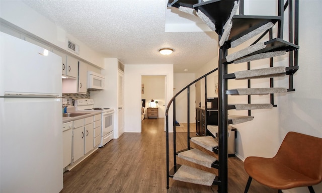 stairs featuring a textured ceiling, wood finished floors, and visible vents