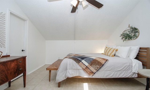 bedroom featuring a ceiling fan, a textured ceiling, light tile patterned floors, and lofted ceiling