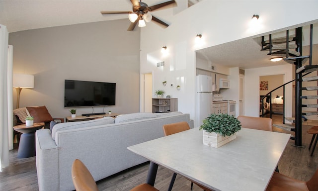dining room with visible vents, dark wood-style flooring, high vaulted ceiling, stairway, and a ceiling fan