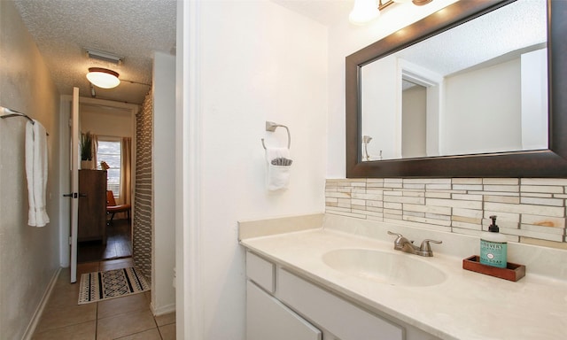 bathroom with visible vents, vanity, a textured ceiling, tile patterned floors, and tasteful backsplash