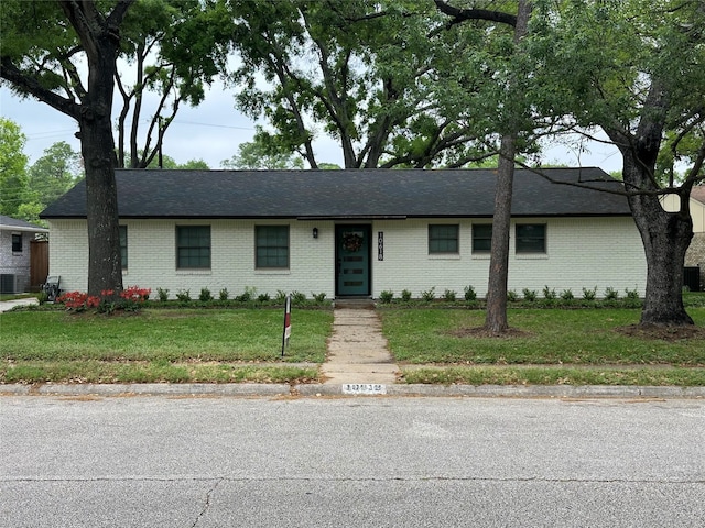 single story home with cooling unit, a front yard, and brick siding