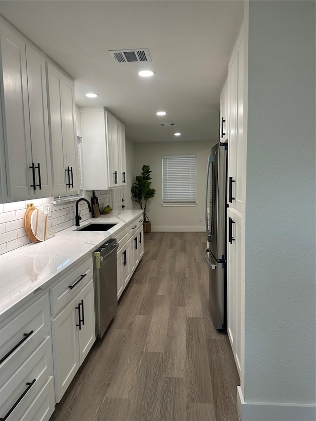 kitchen with baseboards, white cabinets, tasteful backsplash, a sink, and stainless steel appliances