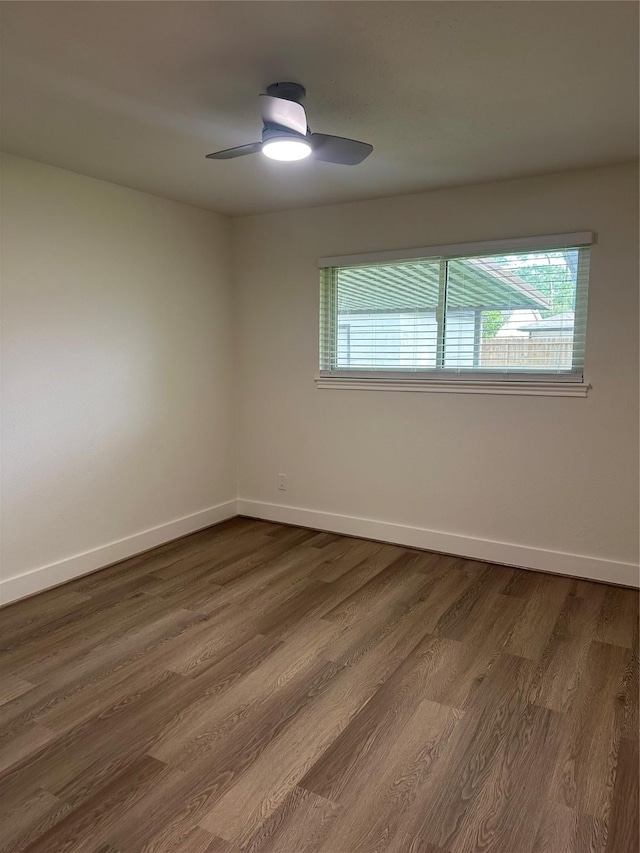 spare room with baseboards, plenty of natural light, and dark wood-style flooring