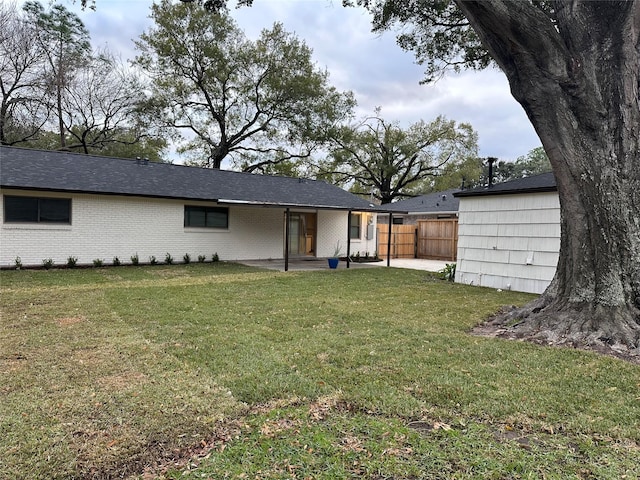 rear view of property with a lawn, a patio, fence, and brick siding