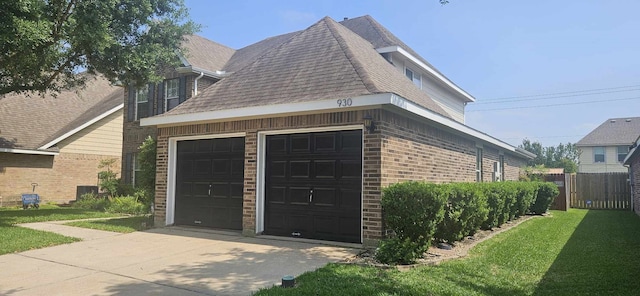 view of property exterior with fence, brick siding, a shingled roof, concrete driveway, and a yard