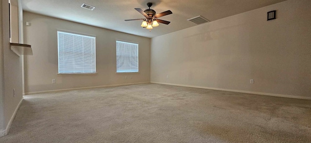 carpeted spare room featuring visible vents, a ceiling fan, and baseboards