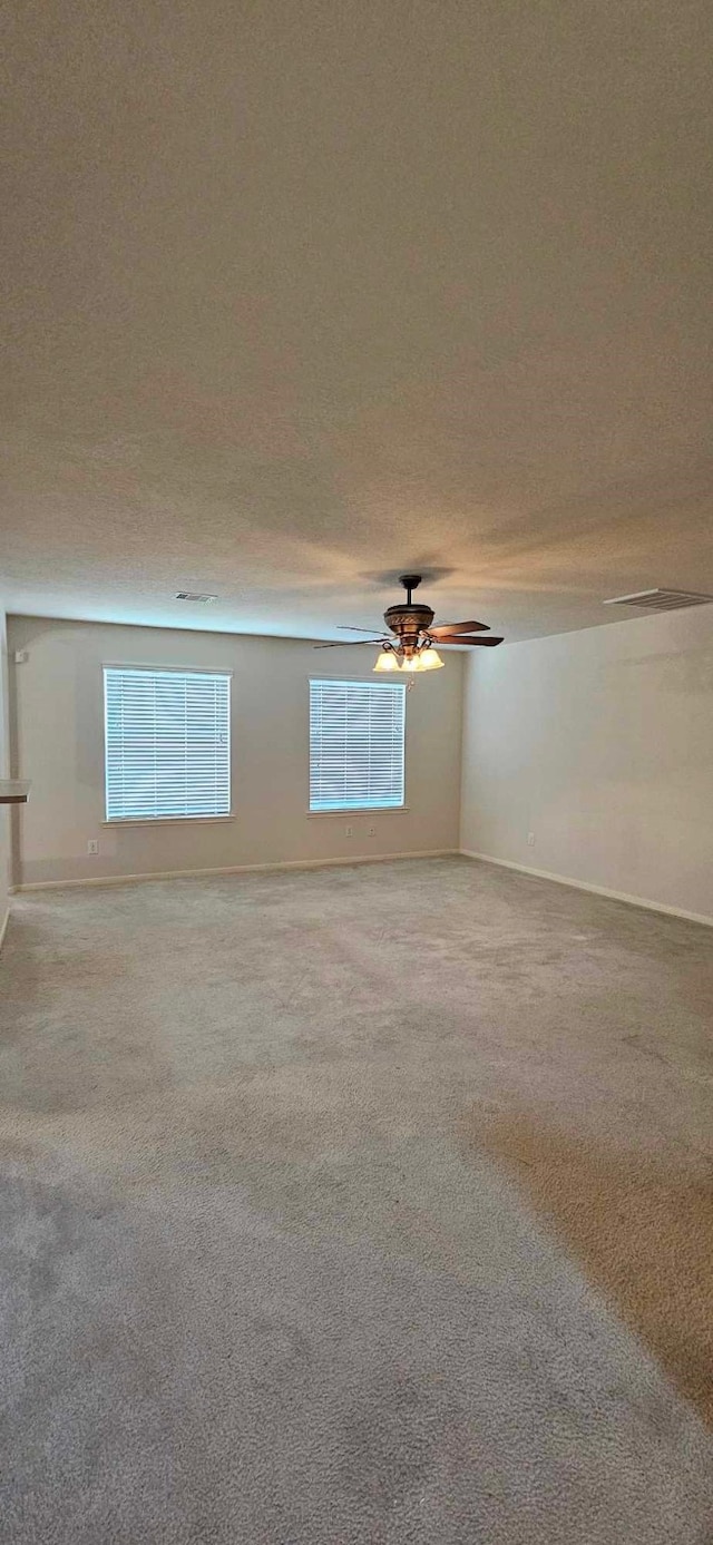 spare room featuring baseboards, a ceiling fan, and light carpet