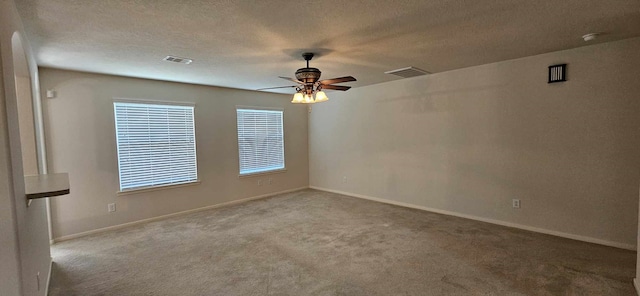 carpeted empty room with visible vents, a textured ceiling, ceiling fan, and baseboards