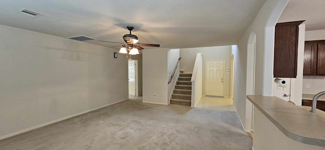living room with stairs, light colored carpet, ceiling fan, and visible vents
