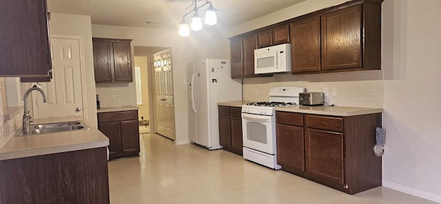 kitchen with dark brown cabinetry, a sink, white appliances, baseboards, and tasteful backsplash