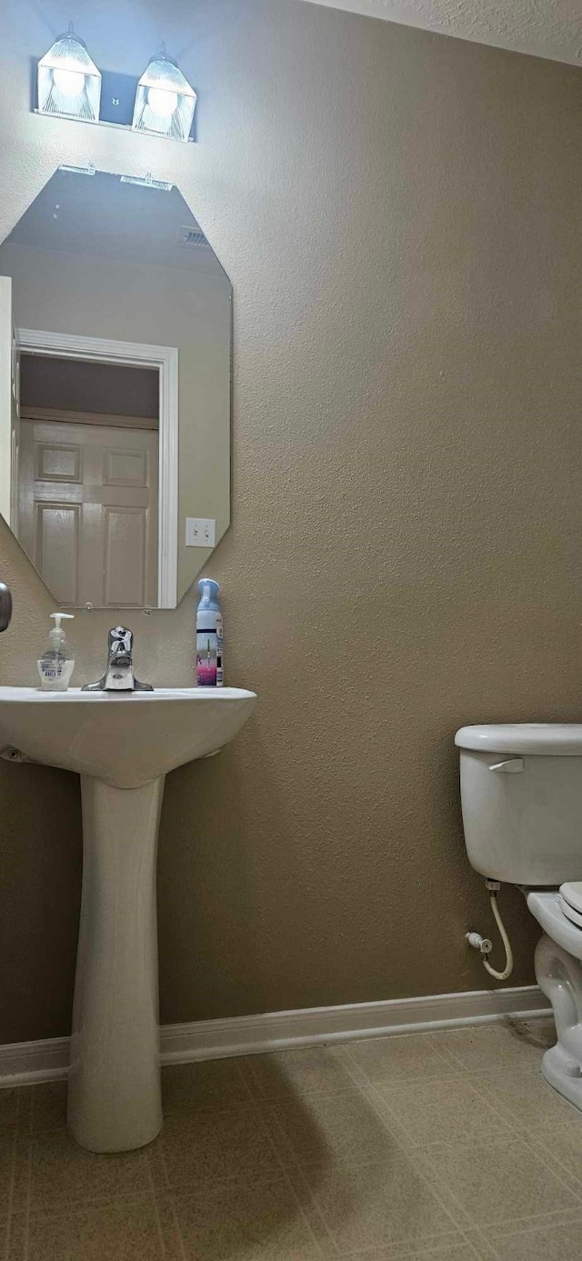 bathroom with baseboards and toilet