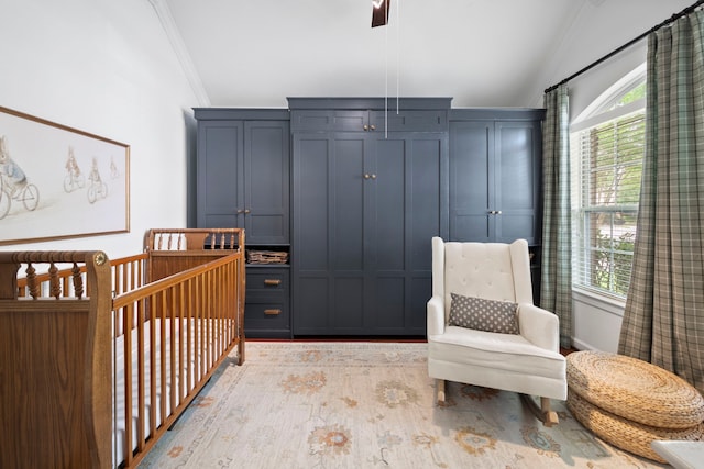 bedroom with crown molding, a crib, lofted ceiling, and light wood-style floors