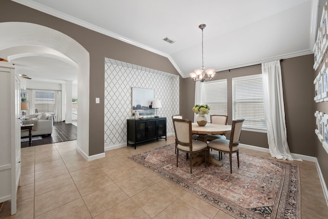 dining area with arched walkways, baseboards, lofted ceiling, an inviting chandelier, and ornamental molding