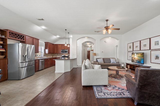 living area with visible vents, a ceiling fan, lofted ceiling, arched walkways, and light wood-style flooring