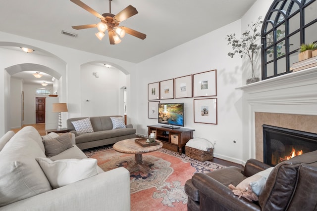 living area with visible vents, arched walkways, ceiling fan, and a fireplace