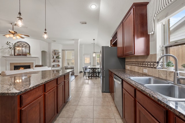 kitchen with plenty of natural light, tasteful backsplash, stainless steel dishwasher, a sink, and open floor plan