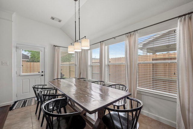dining space with baseboards, visible vents, light tile patterned floors, and lofted ceiling