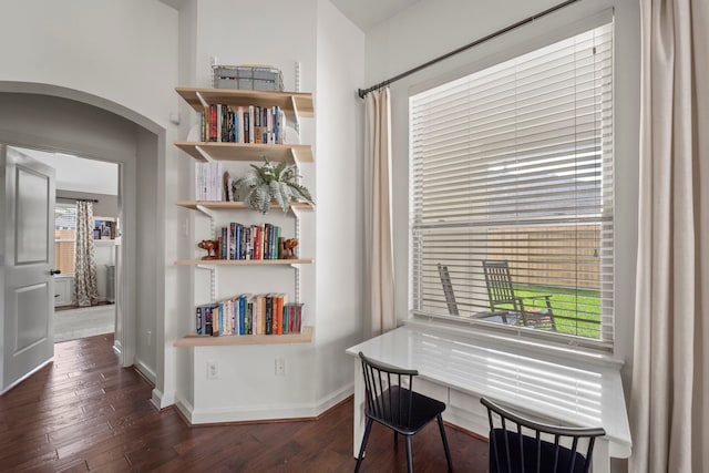 office featuring baseboards, plenty of natural light, arched walkways, and dark wood-type flooring