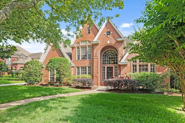 tudor-style house with brick siding and a front lawn