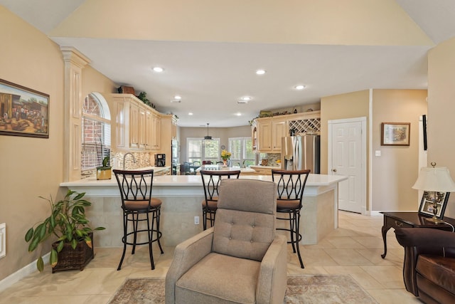 kitchen featuring light countertops, a peninsula, a breakfast bar, and stainless steel fridge with ice dispenser