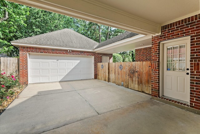 garage with concrete driveway and fence