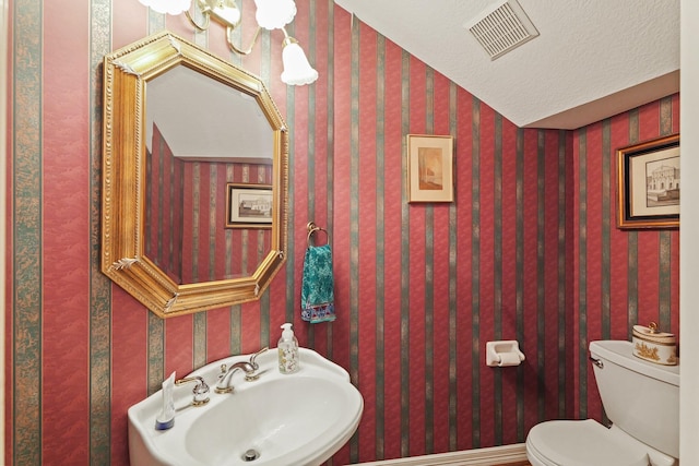 half bathroom with a sink, toilet, and visible vents