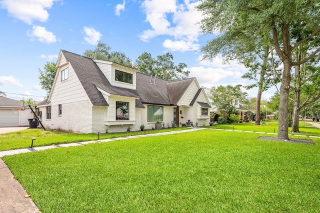 view of front facade featuring brick siding, a shingled roof, and a front yard