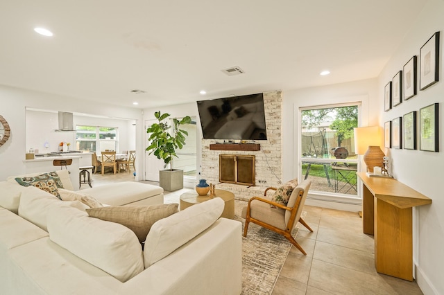 living room featuring recessed lighting, light tile patterned floors, a healthy amount of sunlight, and a fireplace
