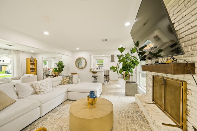 living room with a fireplace with raised hearth, visible vents, and recessed lighting
