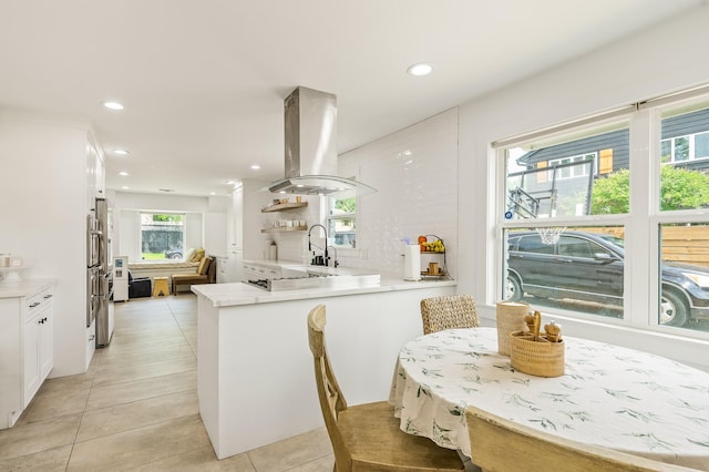 kitchen featuring island exhaust hood, white cabinetry, plenty of natural light, and light tile patterned floors