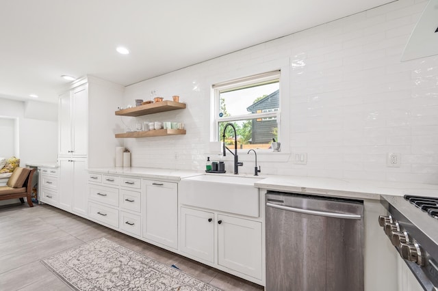 kitchen featuring backsplash, stainless steel dishwasher, stove, light stone countertops, and a sink