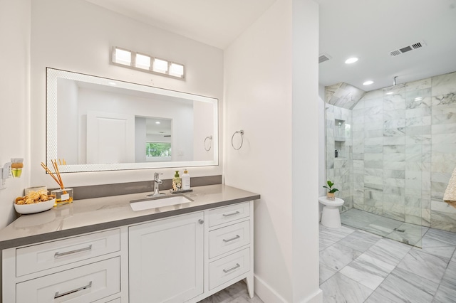 bathroom featuring a tile shower, vanity, marble finish floor, baseboards, and visible vents