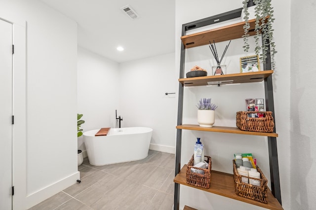 bathroom featuring a freestanding tub, baseboards, tile patterned floors, and visible vents