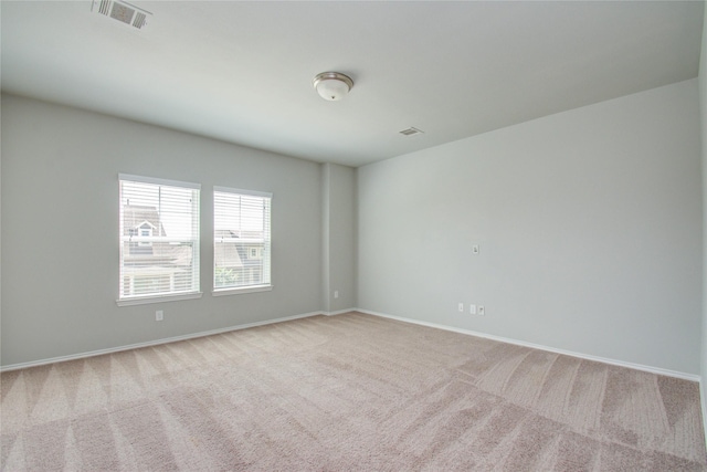 carpeted spare room featuring baseboards and visible vents
