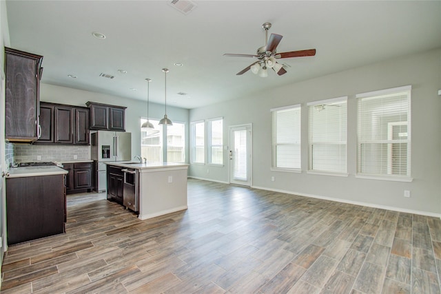 kitchen with a ceiling fan, visible vents, light countertops, open floor plan, and stainless steel appliances