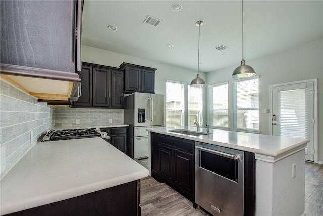 kitchen featuring wood finished floors, light countertops, a sink, backsplash, and stainless steel appliances